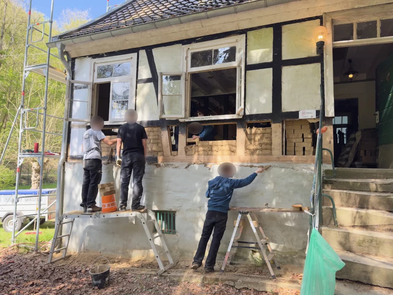 Helfende beim Ausmauern der Gefache an der Fassade.